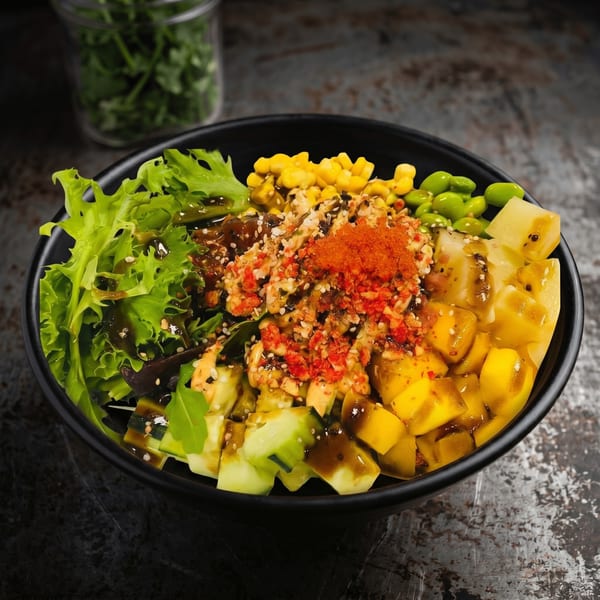 A colorful poke bowl with lettuce, corn, edamame, mango, cucumber, and red roe.